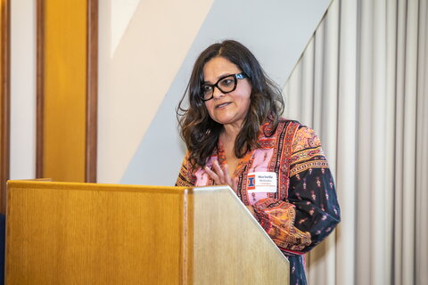 Woman in glasses stands at podium