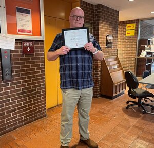 Man poses with award