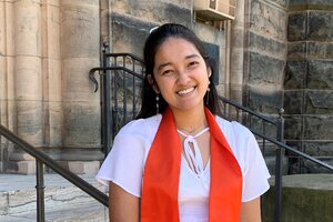 Smiling young woman with dark hair, a white blouse, and an orange graduation stole 