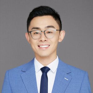 Smiling, dark-haired man in blue suit and glasses 