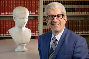 Smiling man in a suit stands in library