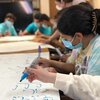 Masked students practice writing in Arabic