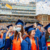 Group of graduates smiling while confetti rains down. Graduate in front snaps a photo on her phone.