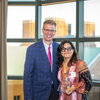 Woman holding award poses for picture with man in front of window