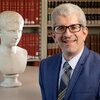 Smiling man in a suit stands in library